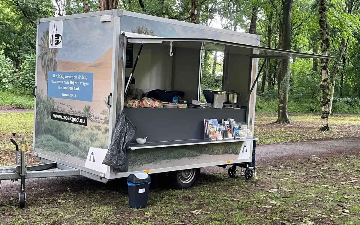 Evangelisatiewagen met maaltijd en lectuur in het park